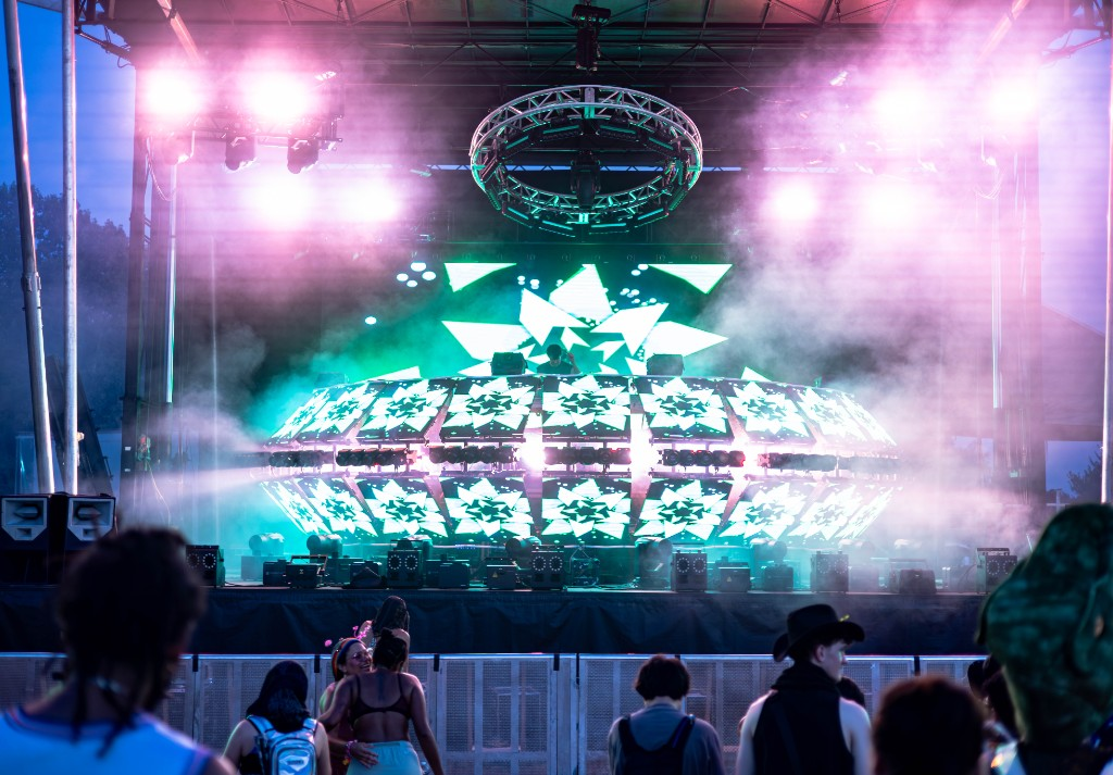 Saucer booth at dusk — starburst LEDs, crowd at the rail