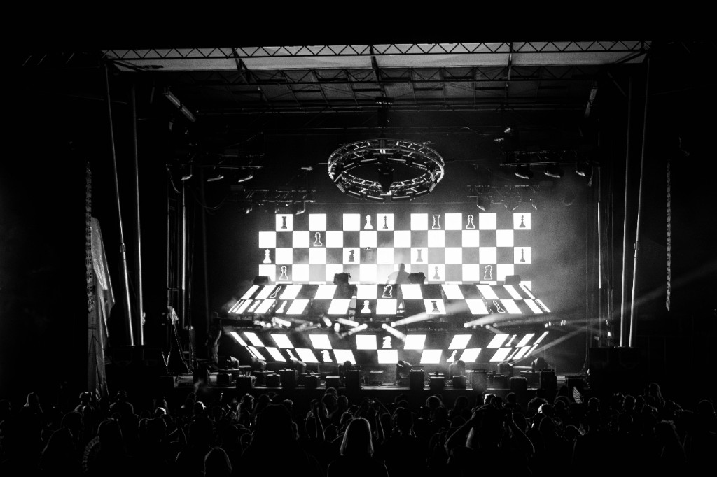 G Jones silhouetted at the decks, radial beams cutting through haze