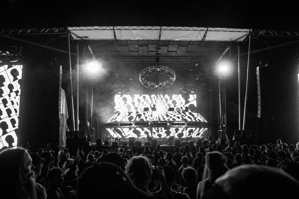 Wide — crowd facing the stage under head-silhouette projections