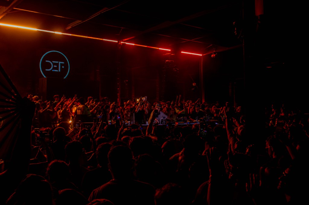DEF logo and orange bars over the warehouse crowd