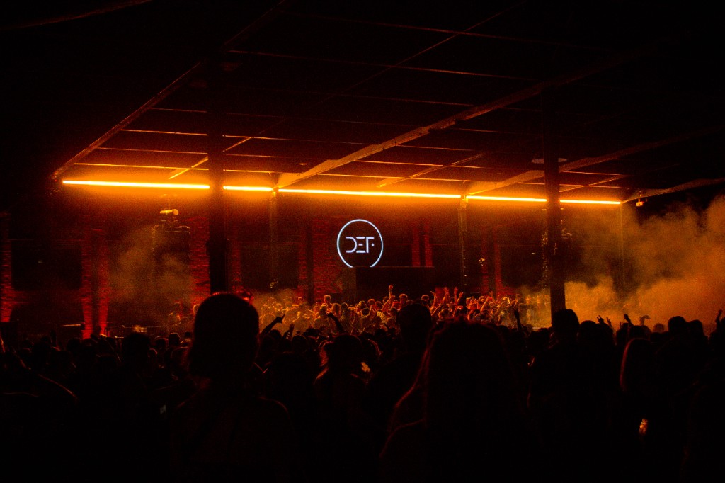 From the back of the hall — orange bar, DEF logo, crowd